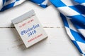 Bavarian tablecloth on wooden background and a tear-off calendar with slogan `Oktoberfest 2018`