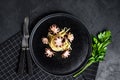 Bavette pasta with baby octopus. Black background. Top view
