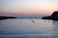 The bay in the cala santandria in ciutadella at twilight with a glowing purple and pink evening sky reflected in dark calm water Royalty Free Stock Photo