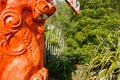 Red carved Maori totem closeup against greenery