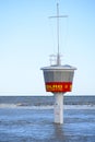 Bay watch tower in the flooded beach at high water against a blue sky in Travemuende, Baltic Sea, the label DLRG - Wasserrettung