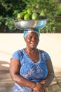 African woman with pelvis on her head with ripe green avocados