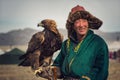 BAYAN-ULGII, MONGOLIA - OCTOBER 01, 2017: Traditional Golden Eagle Festival. Unknown Mongolian Hunter Posing With Great Golden Ea