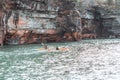 A group of happy, smiling kayakers explore the Apostle Islands sea caves on a fall day