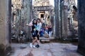 Bayon temple, head and faces made in stone. Tourist visiting and taking pictures.
