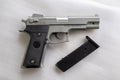 BB Gun, Old Airsoft Pistol Toy and Magazine with BB Gun Bullets on White Foam Background