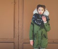 Bbeautiful unusual girl in a green jacket next to the brown door Royalty Free Stock Photo