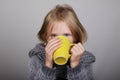 Bblond hair little girl a cup of hot tea in hands. Sick child. Child winter flu health care concept Royalty Free Stock Photo