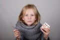 Bblond hair little girl holding medicine and thermometer in a hand. Sick child. Child winter flu health care concept Royalty Free Stock Photo