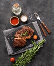 BBQ  beef steak grill with sauce, oil, salt and rosemary on black slate on dark  background Royalty Free Stock Photo