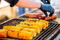 BBQ corn. Hands in gloves flip corn on an open barbecue fire. Corn on a charcoal grill.