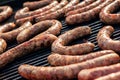 BBQ with fiery sausages on the grill. Red baked delicious juicy sausages in row. Tasty sausage preparing on a barbecue grill.