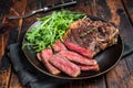 BBQ Grilled Wagyu New York beef meat steak or Striploin steak in a plate with salad. Wooden background. Top view