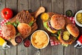 BBQ hamburger table scene, top view over dark wood