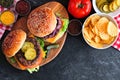 BBQ hamburgers with potato chips, top view table scene on slate