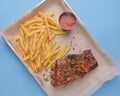 BBQ marinated spareribs and french fries with sauce. Barbecue cooked ribs with spice and sauce served on a metal tray Royalty Free Stock Photo