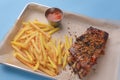 BBQ marinated spareribs and french fries with sauce. Barbecue cooked ribs with spice and sauce served on a metal tray