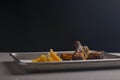 BBQ marinated spareribs with hot spice sauce and french fries served on a gray metal tray over grey textured background. Royalty Free Stock Photo