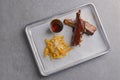 BBQ marinated spareribs with hot spice sauce and french fries served on a gray metal tray over grey textured background. Royalty Free Stock Photo