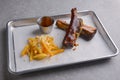 BBQ marinated spareribs with hot spice sauce and french fries served on a gray metal tray over grey textured background. Royalty Free Stock Photo