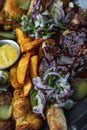 BBQ meat with potatoes and sauce on a plate. Close-up. Top view. Vertical Royalty Free Stock Photo