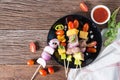 Bbq meat on sticks, kebab skewers with vegetable sticks and tomato sauce on wooden background. Royalty Free Stock Photo