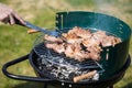 Bbq pork meat cooking outdoors on a portable grill