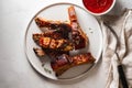 Bbq pork ribs with chili sauce on white plate. Pork ribs on slate background. Copy space. Royalty Free Stock Photo