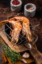 BBQ roasted Giant shrimps Langoustine on grill with herbs. Dark background. Top view