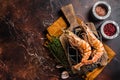 BBQ roasted Giant shrimps Langoustine on grill with herbs. Dark background. Top view. Free copy space