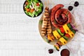 Summer BBQ sausage, pork skewers and vegetable kebabs with salad on a white wood background Royalty Free Stock Photo