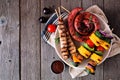 Summer BBQ sausage, pork skewers and vegetable kebabs with salad on a dark wood background Royalty Free Stock Photo