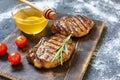 Bbq, Grilled beefsteaks, rosemary, honey, wooden cutting board, dinner preparation, closeup. copy space, selective focus, Royalty Free Stock Photo