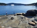 Two fishing boys standing on an unusual wavelike rock formation by passing ferry boat Royalty Free Stock Photo