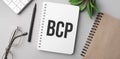 bcp is written in a white notebook with calculator, craft colored notepad, plant, black marker and glasses Royalty Free Stock Photo