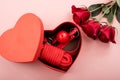 Bdsm set in a box in the form of a heart and red roses on a pink background. Valentine's day gift idea