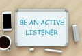 Be An Active Listener, message on whiteboard, smart phone and coffee on table.