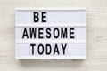 `Be awesome today` word on lightbox over white wooden background, from above.