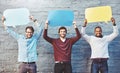 Be bold and speak your mind. Portrait of a group of young men holding speech bubbles against a brick wall.