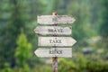 Be brave take risks text on wooden signpost outdoors in the rain