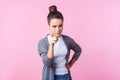 Be careful! Portrait of brunette teenage girl looking angry and pointing finger at camera. isolated on pink background