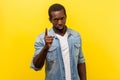 Be careful! Portrait of strict bossy young man standing with warning gesture. indoor studio shot isolated on yellow background