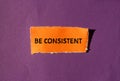 Be consistent words written on orange torn paper with purple background