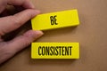 Be consistent words written on wooden blocks with brown background