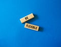 Be Flexible symbol. Wooden blocks with words Be Flexible. Businessman hand. Beautiful blue background. Business and Be Flexible