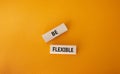 Be Flexible symbol. Wooden blocks with words Be Flexible. Businessman hand. Beautiful orange background. Business and Be Flexible