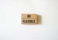 Be Flexible symbol. Wooden blocks with words Be Flexible. Businessman hand. Beautiful white background. Business and Be Flexible