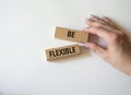 Be Flexible symbol. Wooden blocks with words Be Flexible. Businessman hand. Businessman hand. Beautiful white background. Business