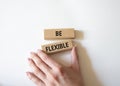 Be Flexible symbol. Wooden blocks with words Be Flexible. Businessman hand. Businessman hand. Beautiful white background. Business