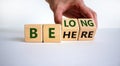 Be here belong symbol. Businessman hand turns cubes and changes words `be here` to `belong`. Beautiful white background. Busin